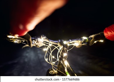 Mountain Bike Handlebar Decorated With Christmas Lights At Snow Road In At Winter Night