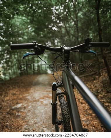 Mountain bike handlebar viewed from the first-person perspective.handlebar and the forest trail. Concept of spending time outdoors while bikeriding
