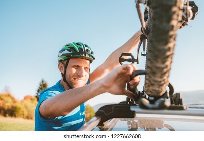 Mountain biker man hold on  his bike on the car roof