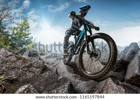 Mountain biker on stone forest trail. Male cyclist rides the rock