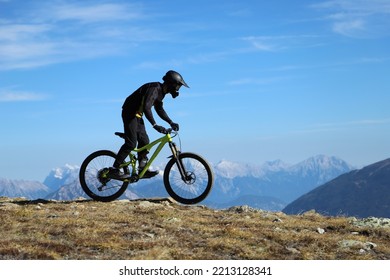 A Mountain Biker On The Summit In The Snowy Alps