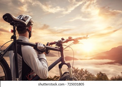 Mountain biker overlooking a valley at sunset