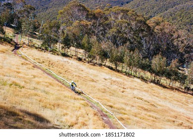 Mountain Bikers Descend Down Thredbo On A Cool Autumn Day In The Snowy Mountains, New South Wales, Australia