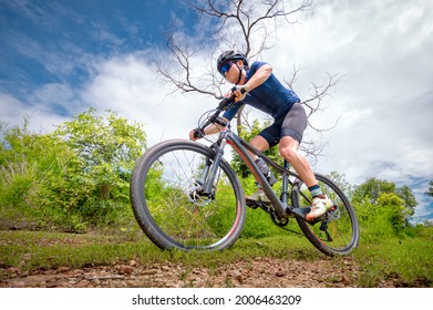 Mountain Bikers Ride MTB, Mountain Bike Downhill To The Extreme. Asian Man Rides MTB, Mountain Bike Downhill In The Wild To Extremes. Extreme Sport And MTB, Mountain Bike Downhill Concept.