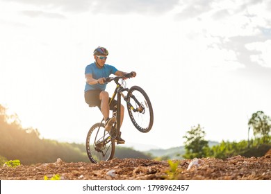 Mountain bikes cyclist cycling, Asian man athlete riding biking jumping on rocky terrain trail, extreme sport wear gear uniform helmet, exciting freedom outdoor sunset nature healthy active lifestyle - Powered by Shutterstock