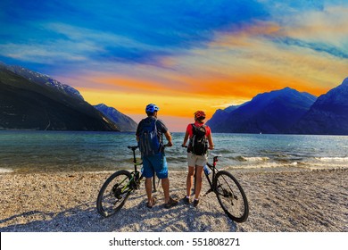 Mountain Biking, Couple With Bikes At Sunset On Lake Garda, Riva Del Garda, Italy