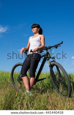Mountain biking happy sportive girl in white shirt relax in meadows sunny countryside