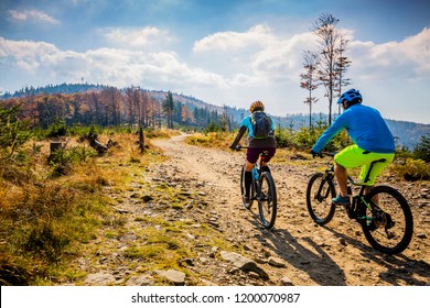 Mountainbike-Mountainbike-Frau und Mann, die auf dem Rad bei Sonnenuntergang Berge Waldlandschaft fahren. Mehrere Radfahrer MTB Enduro-Flussweg. Sportliche Aktivitäten im Freien.