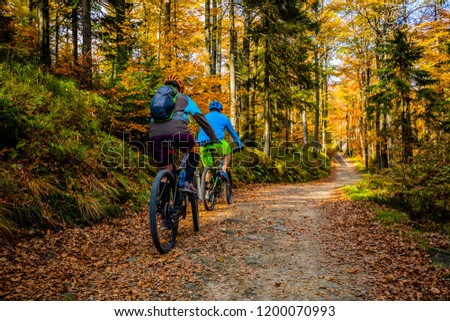 Mountain biking woman and man riding on bikes at sunset mountains forest landscape. Couple cycling MTB enduro flow trail track. Outdoor sport activity.