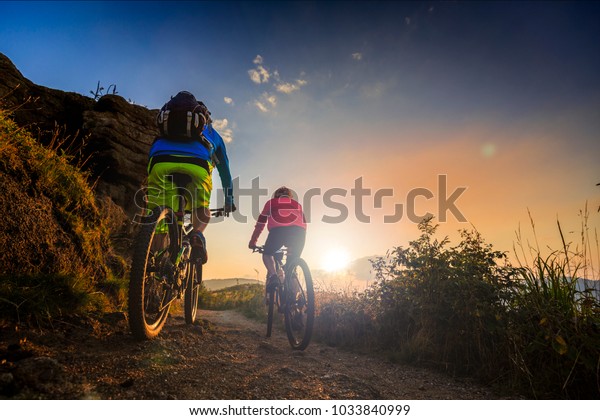 夕焼けの山林景観で 自転車に乗るマウンテンバイクの女性と男性 Mtbエンドルーフロートラックのサイクルを組み合わせます 野外スポーツ活動 の写真素材 今すぐ編集