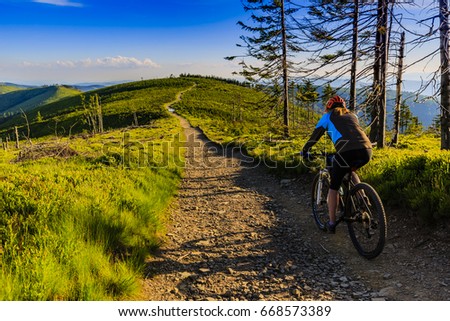 Mountain biking women riding on bike in summer mountains forest landscape. Woman cycling MTB flow trail track. Outdoor sport activity.