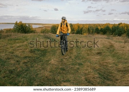 mountain biking.A male cyclist in sports gear rides a mountain bike over rough terrain in autumn, behind a forest and a lake