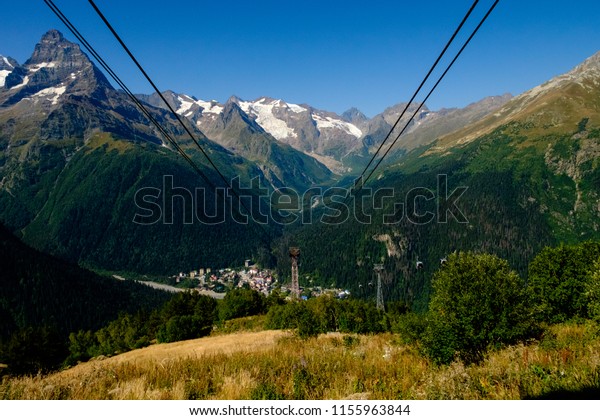 Mountain cable car in the mountains. Houses in\
the background of\
mountains.