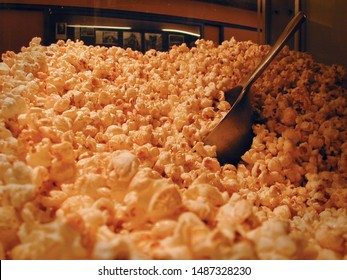 Mountain Of Cinema Popcorn In A Popcorn Machine With A Shovel / Scoop In The Movie Theatre Lobby / Foyer - Warm Light