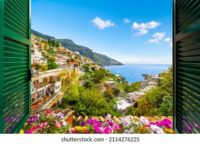 Mountain, city and sea view through an open window with shutters of the city of Positano on the Amalfi Coast of Southern Italy during summer.	
