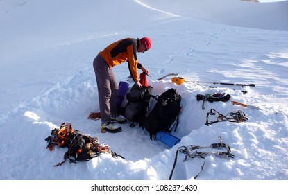 mountain climber getting ready for a cold bivy night in a snowhole on a glacier in the Alps