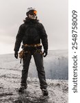 Mountain climber wearing protective gear standing on glacier and preparing for ice climbing