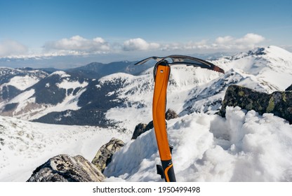 Mountain Climbing Pick Axe In The Snow. Ice Axe In The Snow Against The Background Of The Mountains