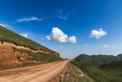 Mountain Country Dirt Road On A Sunny Day.Blue Sky With Clouds.Travel To The Wild.