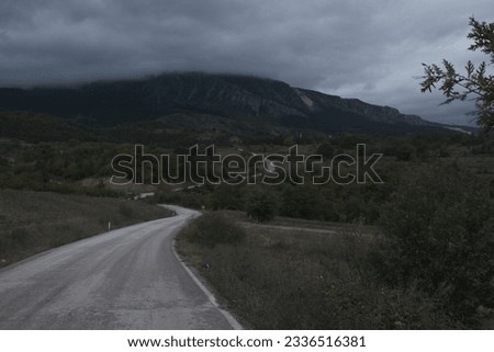 a mountain covered with fog at the end of a winding road