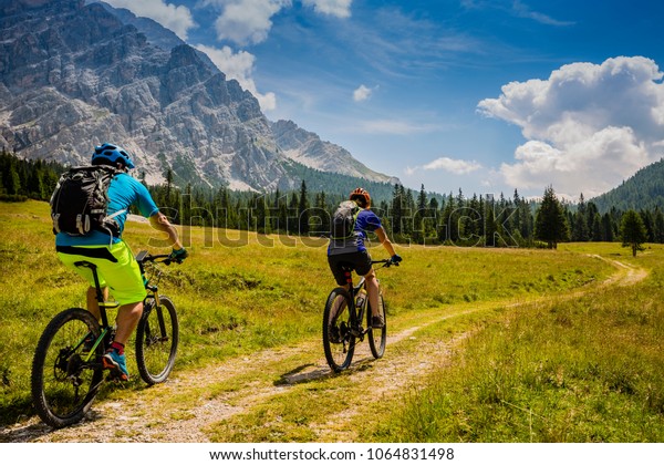 Mountain cycling couple with bikes on track,\
Cortina d\'Ampezzo, Dolomites,\
Italy