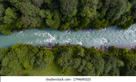 Mountain emerald river with stone coast and forest / strong stream with twists of crystal clear mountain river. Aerial drone top down view at summer sunny day