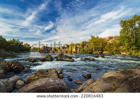 Mountain fast flowing river stream of water in the rocks with blue sky