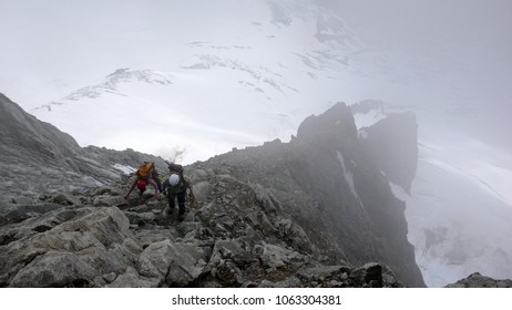 mountain guide and client heading towards a high alpine summit on a foggy day