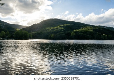 Mountain lake with cloudy sky, backlit.