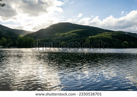 Mountain lake with cloudy sky, backlit.