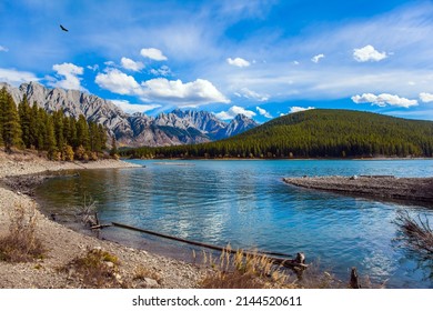Mountain lake with emerald glacial water. The Canadian Rockies. Autumn day in Indian summer. Mountain slopes overgrown with coniferous forests. The concept of active, ecological and photo tourism