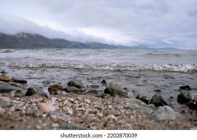 Mountain lake shore. Rocky shore of the reservoir. Mountains with clouds.  Lake Sevan in Armenia.