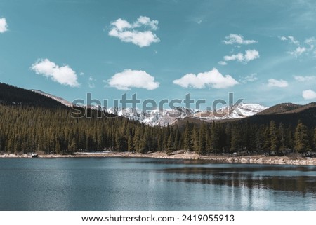 Mountain lake view with trees and a bright sky 
