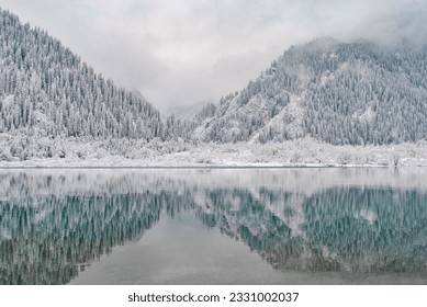 Mountain lake in winter. Snow-covered mountains are reflected in the water. Winter landscape. - Powered by Shutterstock