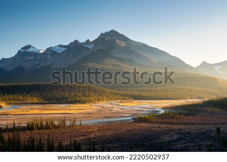 Mountain landscape at dawn. Sunbeams in a valley. Rivers and forest in a mountain valley at dawn. Natural landscape with bright sunshine. High rocky mountains. Banff National Park, Alberta, Canada. 