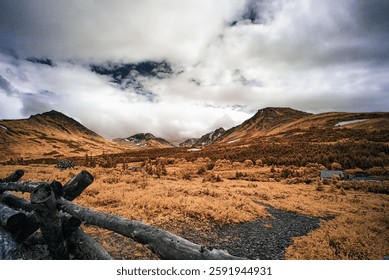 A mountain landscape with dramatic clouds and vibrant foliage with dramatic cloudy sky