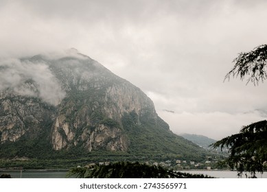Mountain landscape featuring clouds obscuring peaks above a serene lake and distant town