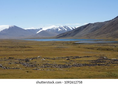 Mountain Landscape With A Lake. Snow Peaks Visible. Summer Morning With Cloudless Sky. Wonderlust Travels. 