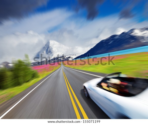 Mountain landscape with road and sports car in\
motion blur