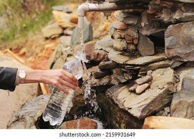 Mountain Mineral Water Source. The Girl Collects Mineral Spring Water