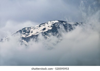 Mountain peak breaking through the solid cloud bank