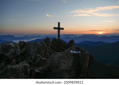 Mountain peak cross silhouetted against a breathtaking sunrise. - Powered by Shutterstock