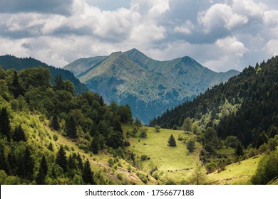 Mountain peak with dramatic sky in the background and a valley with trees in the foreground!