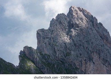 Mountain peak, over cloudy sky, illuminated by a sunbeam filtering through clouds, on a stormy weather day in the Alps - Shutterstock ID 1358842604