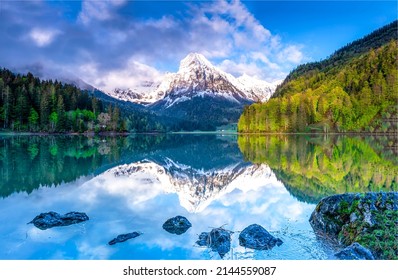 A mountain peak is reflected in a mountain lake. Beautiful mountain lake landscape. Mountain forest reflected in lake water. Forest lake in mountains