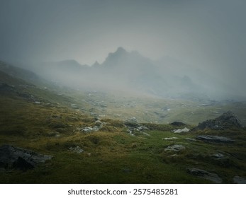 Mountain peak seen through the dense fog. Rainy scene in the mounts, hiking in the mist landscape