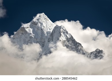 Mountain Peak Visible High In The Sky Through The Clouds.