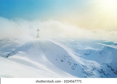 Mountain peaks covered by snow and Heroes cross on top of Bucegi illuminated by sunset light in winter season - Powered by Shutterstock