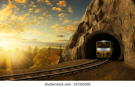 Horská železnice s vlakem v tunelu. Západ slunce krajina pod velkou skálou.