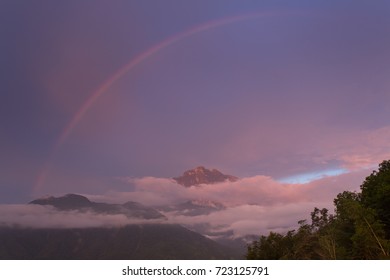 Mountain with rainbow and covered with cloud during evening time.